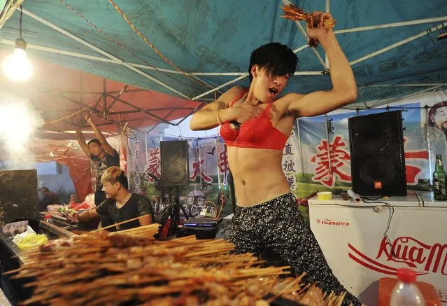 A man wearing a bra dances to attract customers at his lamb kebabs stand in Yongkang, Zhejiang province October 15, 2014. Picture taken October 15, 2014. (Photo by Reuters/Stringer)