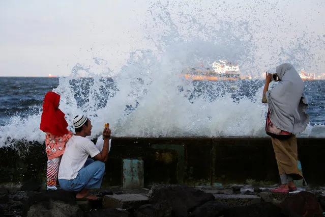 A family takes pictures as waves crash over a concrete sea wall at Muara Baru port in Jakarta, Indonesia, July 14, 2016. (Photo by Reuters/Beawiharta)