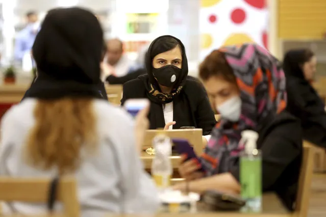 Women wearing protective face masks to help prevent spread of the coronavirus sit at a shopping center food court, in Tehran, Iran, Wednesday, August 19, 2020. Iran surpassed 20,000 confirmed deaths from the coronavirus on Wednesday, the health ministry said — the highest death toll for any Middle East country so far in the pandemic. (Photo by Ebrahim Noroozi/AP Photo)