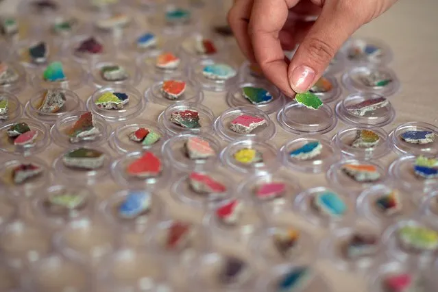 A woman sorts small stones from the former Berlin Wall in transparent plastic cases at Pawlowski, a wholesale souvenir supplier, in Berlin, Germany, 4 November 2014. The souvenir retailer produces and distributes around 20 Wall-themed products. (Photo by Matthias Balk/EPA)