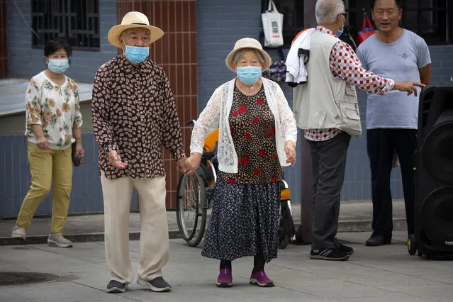 An elderly couple wearing face masks to protect against the coronavirus walks at a public park in Beijing, Saturday, September 12, 2020. Even as China has largely controlled the outbreak, the coronavirus is still surging across other parts of the world. (Photo by Mark Schiefelbein/AP Photo)