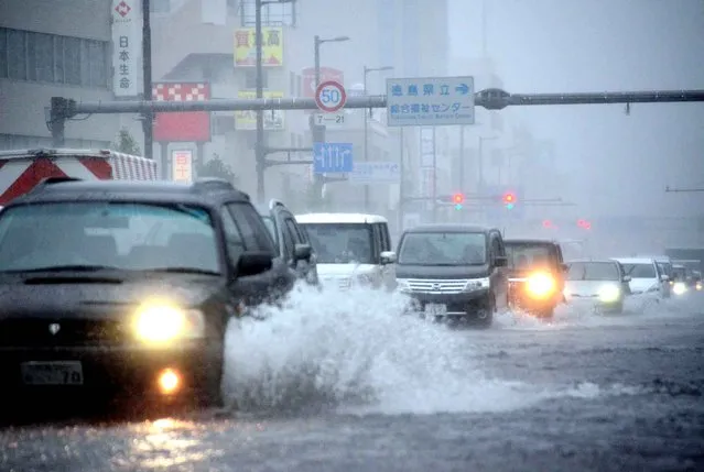 Vehicles drive through a flooded street as typhoon Malakas moves across Tokushima on September 20, 2016. A powerful typhoon ripped into southern Japan on September 20, dumping torrential rains on the region that left some communities partially submerged and forced dozens of flights to be cancelled. (Photo by JIJI Press/AFP Photo)