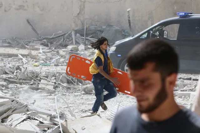 A man runs with a stretcher in a damaged site after airstrikes on the rebel held al-Qaterji neighbourhood of Aleppo, Syria September 21, 2016. (Photo by Abdalrhman Ismail/Reuters)