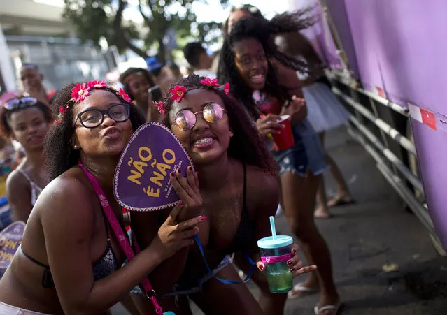 In this February 3, 2018 photo, a woman holds a fan that reads “No' is 'no!” as she strike a pose with friends, during the Simpatia e Quase Amor in Rio de Janeiro, Brazil. Security officials and several non-government groups that have launched campaigns against harassment of women. (Photo by Silvia Izquierdo/AP Photo)