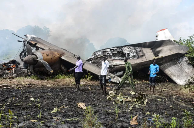 People stand near the cargo plane belonging to a local operator that crashed seven kilometres west of the Juba International airport shortly after takeoff on August 22, 2020, killing four passengers and three crew, with one survivor. According to the Transport Minister Madut Biar Yol, the crew members were Russian while the passengers were all South Sudanese. The plane owned by local company South West Aviation had been carrying cash to the Wau region in the country's northwest for Juba-based Opportunity Bank. (Photo by David Dhal Malual/AFP Photo)
