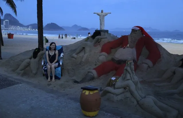 A woman poses for a photo next to a Santa Claus sand sculpture placed on Copacabana beach in Rio de Janeiro, November 25, 2014. (Photo by Pilar Olivares/Reuters)