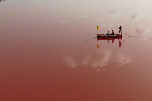 A boat sails on the Lake Retba, around 35 kilometers away from Dakar in Senegal, on July 3, 2025. Lake Retba, also known as The Pink Lake, which lost its color due to excessive rainfall in Senegal, has regained its color after a long period of pollution-induced fading. The lake, which is among the saltiest lakes in the world and turns pink thanks to the algae named 'Dunaliella salina', is important for both tourism and the economy of the region. (Photo by Cem Ozdel/Anadolu via Getty Images)