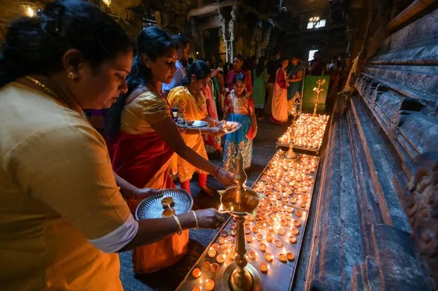 Devotees light oil lamps while offering prayers during New Year's Day at a Hindu temple in Colombo on January 1, 2023. (Photo by Ishara S. Kodikara/AFP Photo)