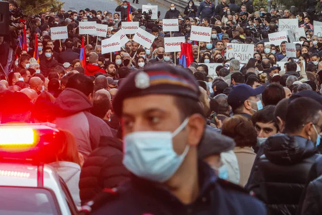 A police officer guards as people gather in a street during a protest against an agreement to halt fighting over the Nagorno-Karabakh region, in Yerevan, Armenia, Thursday, November 12, 2020. Thousands of people flooded the streets of Yerevan once again on Wednesday, protesting an agreement between Armenia and Azerbaijan to halt the fighting over Nagorno-Karabakh, which calls for deployment of nearly 2,000 Russian peacekeepers and territorial concessions. Protesters clashed with police, and scores have been detained. (Photo by Dmitri Lovetsky/AP Photo)