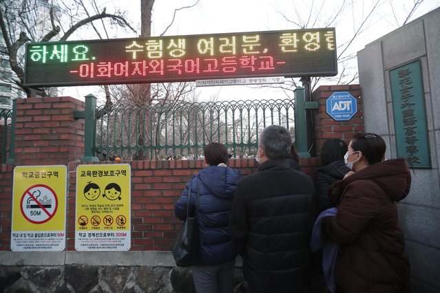 Parents watch their children head to the college entrance exam in front of a high school in Seoul, South Korea, Thursday, December 3, 2020. The electric board reads: “Welcome to students”. (Photo by Ahn Young-joon/AP Photo)
