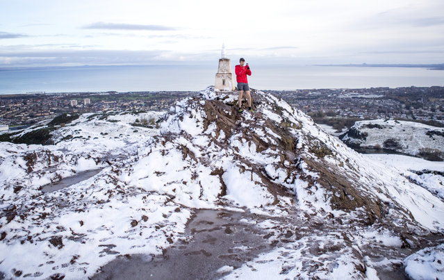 A fell runner takes a photo on a smart phone in the snow on the summit of Arthur's Seat in Holyrood Park, Edinburgh on December 3, 2020. (Photo by Jane Barlow/PA Images via Getty Images)