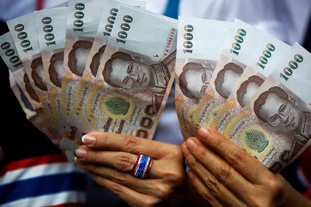 Anti-government protesters hold Thai baht banknotes ready to donate to their leader marching in downtown Bangkok February 7, 2014. (Photo by Damir Sagolj/Reuters)