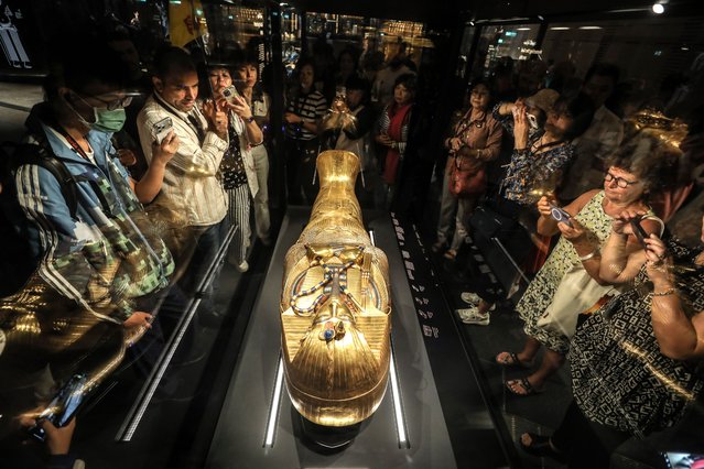 Visitors look at the golden coffin of Tutankhamun, the famous pharaoh of Ancient Egypt, on display at the Grand Egyptian Museum, which sheds light on thousands of years of Egyptian history and houses hundreds of historical artifacts near the Giza Pyramids, in Giza, Egypt on November 4, 2025. Tutankhamun ruled during the New Kingdom period of Ancient Egypt, and ascended the throne at the age of 9 before dying suddenly at the age of 19, has 7,000 square meters of exhibition space dedicated to him in the museum. (Photo by Mohamed Elshahed/Anadolu via Getty Images)