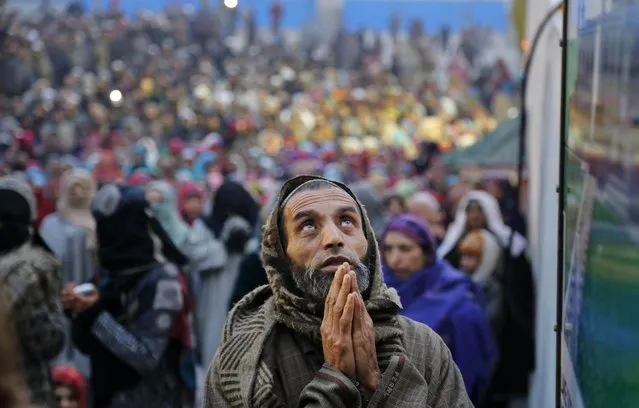 A Kashmiri devotee prays as a head priest displays a holy relic of Islam's Prophet Muhammed at the Hazratbal shrine on Eid-e-Milad, the birth anniversary of the Prophet, in Srinagar, India, Sunday, January 4, 2015. Thousands of Kashmiri Muslims gathered at the Hazratbal shrine which houses a relic believed to be a hair from the beard of the prophet. (Photo by Mukhtar Khan/AP Photo)