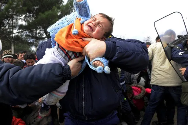 A Greek policeman carries away a child  during a scuffle with Syrian, Iraqi and Afghan refugees at the Greek-Macedonian borders near the village of Idomeni, Greece November 22, 2015. (Photo by Alexandros Avramidis/Reuters)