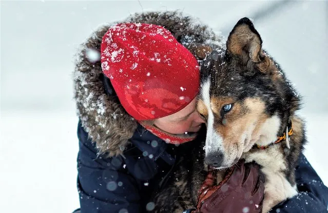 Kings Bay AS accountant Sunniva Berge Mo, 33, hugs her dog Zelda, at the dog yard in Ny-Aalesund, Svalbard, Norway on April 9, 2023. Ny-Alesund has only about 35 year-round residents but, in summer, the population swells to more than 100 as scientists fly in from across the world to the town, where the daily life centers around its diversions – a sauna, a sled dog yard, and a weekly nighttime gathering called “Strikk og Drikk”, or “Knit and Sip”, during which residents stitch sweaters over a glass of wine. (Photo by Lisi Niesner/Reuters)