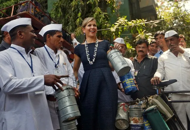 Queen Maxima of the Netherlands holds a tiffin as she poses with Dabbawalas, also known as tiffin carriers, during their meeting in Mumbai, India, May 30, 2018. (Photo by Francis Mascarenhas/Reuters)