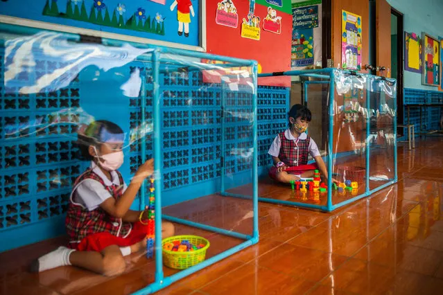 Thai kindergarteners wear face masks as they play in screened-in play areas used for social distancing at the Wat Khlong Toey School on August 10, 2020 in Bangkok, Thailand. (Photo by Lauren DeCicca/Getty Images)