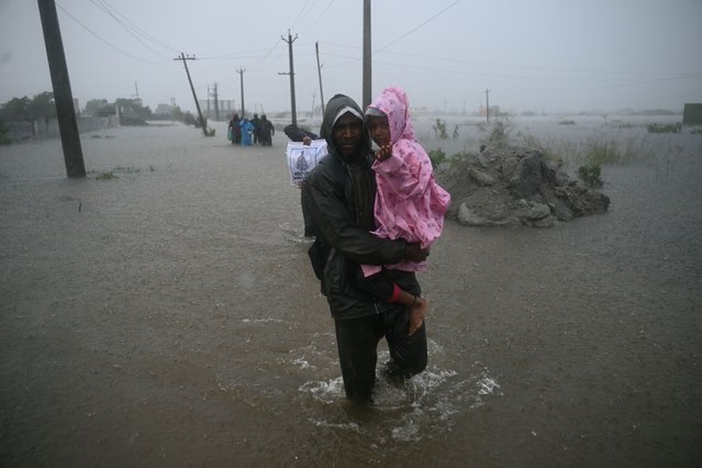 People wade across floodwater, amid heavy rain due to cyclone Ditwah, on the outskirts of Chennai, on December 3, 2025. (Photo by R.Satish Babu/AFP Photo)