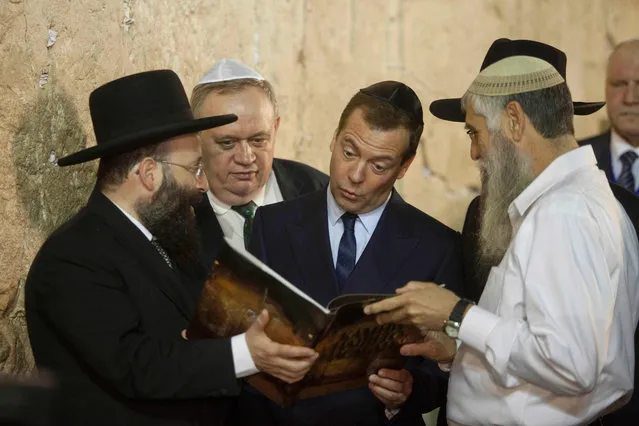 Russian Prime Minister Dmitry Medvedev receives a book during his visit at the Western Wall, the holiest site where Jews can pray in Jerusalem' s Old City in Jerusalem, Thursday, November 10, 2016. Medvedev is on a high level visit to Israel to explore issues of mutual interest. (Photo by Dan Balilty/AP Photo)