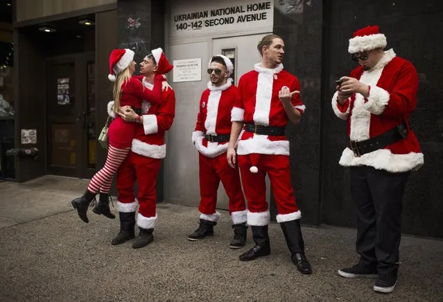 Revelers dressed in holiday theme costumes gather as they participate in SantaCon in New York Saturday, December 12, 2015. (Photo by Andres Kudacki/AP Photo)