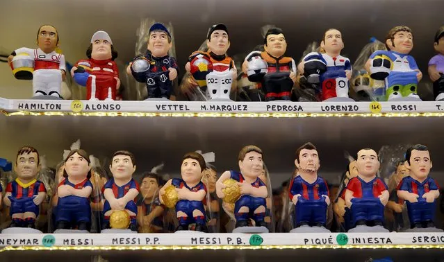 Clay "caganers" representing FC Barcelona's players (down L-R) Neymar, Lionel Messi, Gerard Pique, Andres Iniesta, Sergio Busquets, (down L-R) F1 drivers Lewis Hamilton, Fernando Alonso, Sebatian Vettel, motoGP riders Marc Marquez, Dani Pedrosa and Valentino Rossi are seen on display at the Santa Llucia Christmas market in central Barcelona, Spain, December 16, 2015. (Photo by Albert Gea/Reuters)