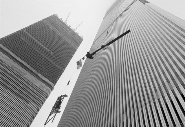 The American flag, attached to a 36-foot-long, four-ton steel column, is hoisted to the top of the north tower building of the World Trade Center in New York City, December 23, 1970. The traditional ceremony, know as topping out, marks the completion of the 1,350-foot structure which is the world's tallest building. (Photo by Anthony Camerano/AP Photo)