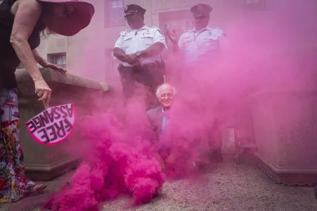 Ben Cohen, co-founder of Ben & Jerry's, sits blocking the entrance to the Department of Justice, as pink smoke is fanned by Jodie Evans, left, co-founder of protest group CODEPINK, before they were detained for blocking the entrance after first burning a replica of the Bill of Rights in protest of the Justice Department's prosecution of Wikileaks founder Julian Assange, Thursday, July 6, 2023, outside the Department of Justice in Washington. (Photo by Jacquelyn Martin/AP Photo)