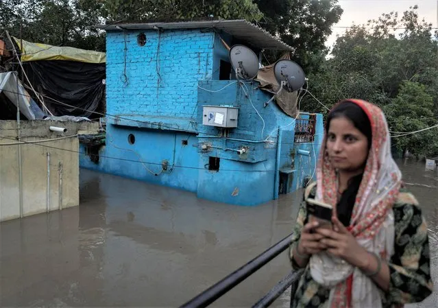 A woman stands next to flooded houses after a rise in the water level of river Yamuna in New Delhi, India on July 12, 2023. (Photo by Adnan Abidi/Reuters)