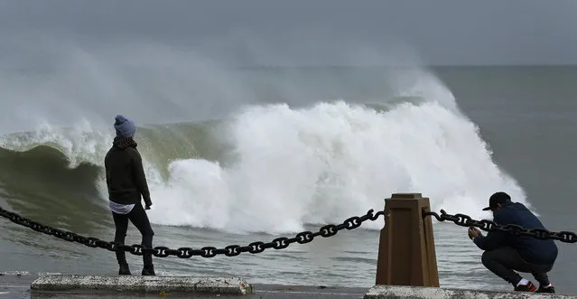 A couple take photos of waves churned by a winter storm at Fort Point on Wednesday, January 6, 2016, in San Francisco Bay. El Nino storms lined up in the Pacific, promising to drench parts of the West for more than two weeks and increasing fears of mudslides and flash floods in regions stripped bare by wildfires. At least two more storms are expected to follow bringing as much as 3 inches of rain. (Photo by Ben Margot/AP Photo)