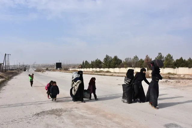 Syrians that evacuated the eastern districts of Aleppo carry their belongings, while walking on a road, in a government held area in Aleppo, Syria in this handout picture provided by SANA on November 29, 2016. (Photo by Reuters/SANA)