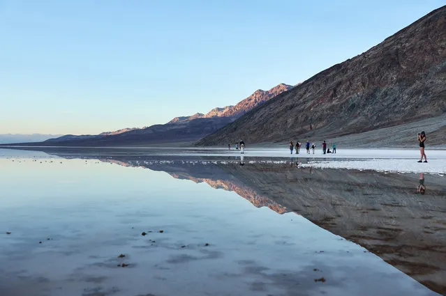 Visitors gather at the sprawling temporary lake at Badwater Basin salt flats, which was caused by flooding in August from Tropical Storm Hilary, at the recently reopened Death Valley National Park on October 21, 2023 in Death Valley National Park, California. The storm delivered a year's worth of rain to Death Valley in a single day and flood damage forced the iconic desert park's closure for eight weeks. Death Valley is the hottest place on Earth and Badwater Basin is located 282 feet below sea level, the lowest elevation in North America. Parts of the park remain closed as repair work continues. (Photo by Mario Tama/Getty Images)