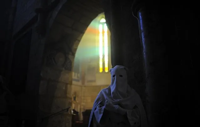 A hooded penitent from “La Borriquita” brotherhood takes part during a Holy Week procession in Cordoba, Spain, Sunday, March 29, 2015. (Photo by Manu Fernandez/AP Photo)