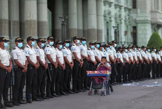Police officers stand guard during a protest to demand the resignation of Guatemalan President Alejandro Giammattei and Attorney General Maria Porras, in Guatemala City, Guatemala on July 31, 2021. (Photo by Sandra Sebastian/Reuters)