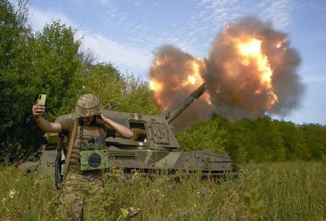 A Ukrainian soldier takes a selfie as an artillery system fires in the front line in Donetsk region, eastern Ukraine, Saturday, September 3, 2022. (Photo by Kostiantyn Liberov/AP Photo)