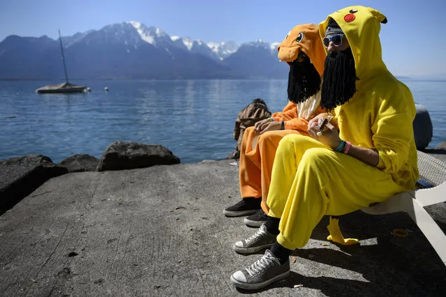 Two people dressed up in funny costumes enjoy the good weather on the shore of Lake Geneva as they attend the Polymanga convention in Montreux, Switzerland, April 6, 2015. The convention gathering manga, video games and Japanese contemporary culture enthusiasts run for four days. (Photo by Laurent Gillieron/EPA)