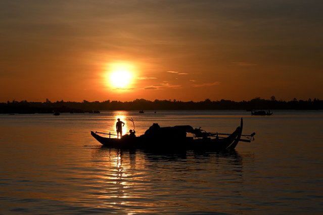 A fisherman sorts out a net on a fishing boat in the Mekong River in Phnom Penh on June 28, 2021. (Photo by Tang Chhin Sothy/AFP Photo)