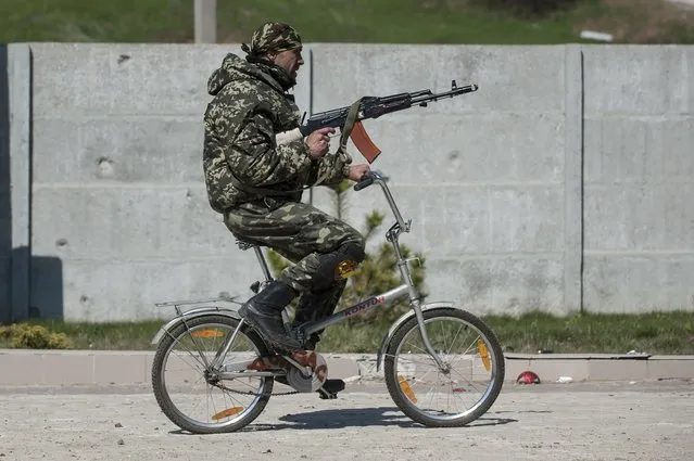 A Ukrainian serviceman rides a bicycle in Shyrokyne, eastern Ukraine, Wednesday, April 15, 2015. Russia and Ukraine agreed in Berlin on Monday to call for the pullback of smaller-caliber weapons from the front lines of the conflict that has claimed more than 6,000 lives. (Photo by Evgeniy Maloletka/AP Photo)