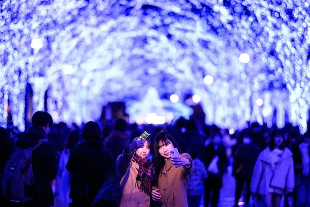 People take pictures with festive light installations, ahead of the Christmas season in Tokyo's Shibuya district on December 21, 2023. (Photo by Philip Fong/AFP Photo)