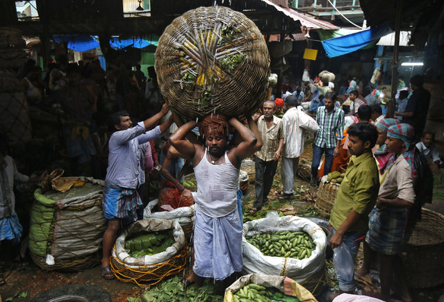 Labourers carry a basket packed with vegetables through a wholesale market in Kolkata, India, February 26, 2016. (Photo by Rupak De Chowdhuri/Reuters)