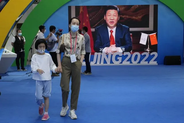 A woman and child wearing masks pass by a screen displaying Chinese President Xi Jinping during the China International Fair for Trade in Services (CIFTIS) in Beijing Sunday, September 5, 2021. An avalanche of changes launched by China's ruling Communist Party has jolted everyone from tech billionaires to school kids. Behind them: Xi's vision of reviving an idealized early era of vigorous party leadership, with more economic equality and tighter control over society and billionaire entrepreneurs. (Photo by Ng Han Guan/AP Photo)