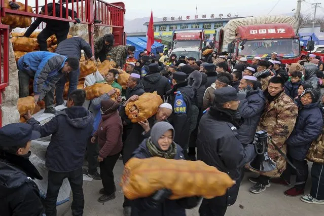Volunteers distribute foods to quake victims at a temporary settlement in Chenjiacun village in Jishishan county in northwest China's Gansu province on Wednesday, December 20, 2023. Hundreds of temporary housing units were being set up in northwest China on Thursday for survivors of an earthquake that destroyed more than 14,000 homes and killed at least 135 people, according to state media reports. (Photo by Chinatopix via AP Photo)