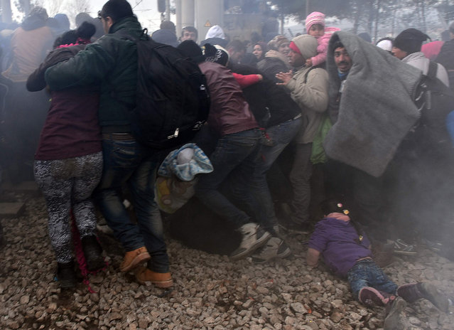 A child lays on the ground as migrants and refugees run away after Macedonian police fired tear gas at hundreds of Iraqi and Syrian migrants who tried to break through the Greek border fence in Idomeni, on February 29, 2016. (Photo by Louisa Gouliamaki/AFP Photo)