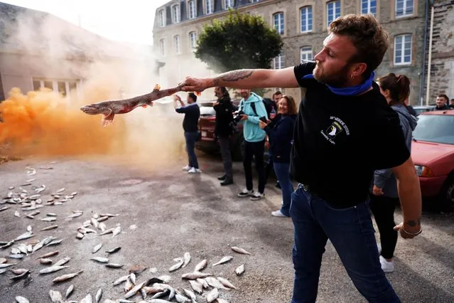 French fishermen throw fish in front of the Regional Committee for Maritime Fisheries building during a protest against offshore wind turbines projects following the call for a national mobilisation launched by the Citizens of the Seas collective, in the port of Cherbourg-en-Cotentin, France, September 24, 2021. (Photo by Stephane Mahe/Reuters)