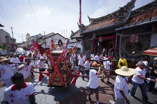 Ethnic Chinese devotees carry a sedan chair during their 9 km procession during Wangkang or “royal ship” festival in Malacca, Malaysia, Thursday, January 11, 2024. The Wangkang festival was brought to Malacca by Hokkien traders from China and first took place in 1854. Processions have been held in 1919, 1933, 2001, 2012 and 2021. (Photo by Vincent Thian/AP Photo)