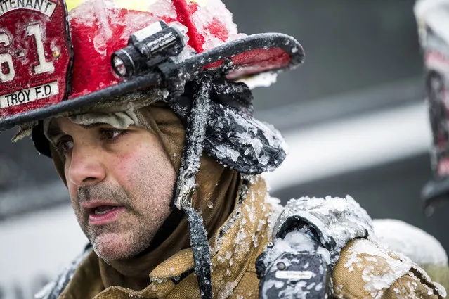 Water from a fire hose freezes atop a firefighter's helmet as he and more than 25 firefighters from eight departments work to contain a large blaze near the U.S. Farathane Corporation building, a plastics and manufacturing supply facility, on Tuesday, February 26, 2019 in Auburn Hills, Mich. No injuries were reported. (Photo by Jake May/The Flint Journal via AP Photo)