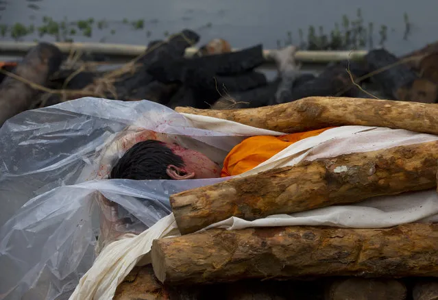 The lifeless body of Umesh, 13, rests on the funeral pyre for cremation at the Pashupatinath temple, on the banks of Bagmati river, in Kathmandu, Nepal, Monday, April 27, 2015. (Photo by Manish Swarup/AP Photo)