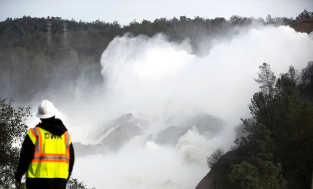 A water utility worker looks towards discharging water as it is released down a spillway as an emergency measure at the Oroville Dam in Oroville, California on February 13, 2017. Almost 200,000 people were under evacuation orders in northern California Monday after a threat of catastrophic failure at the United States' tallest dam. Officials said the threat had subsided for the moment as water levels at the Oroville Dam, 75 miles (120 kilometers) north of San Francisco, have eased. But people were still being told to stay out of the area. (Photo by Josh Edelson/AFP Photo)