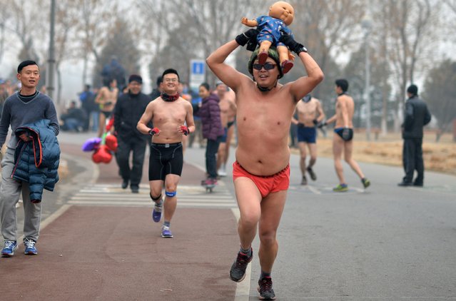 This picture taken on February 23, 2014 shows a participant (C) running with a baby doll in the annual 3.5 km Undie Run held in the Olympic Forest Park smog-covered Beijing. (Photo by AFP Photo/STR)
