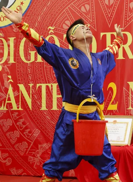 Do Dang Tuan uses his right eyelids to pull up a bucket of water attached to a rope, as he performs during a showcase of traditional Thien Mon Dao kung fu at Du Xa Thuong village, southeast of Hanoi, Vietnam May 10, 2015. (Photo by Reuters/Kham)